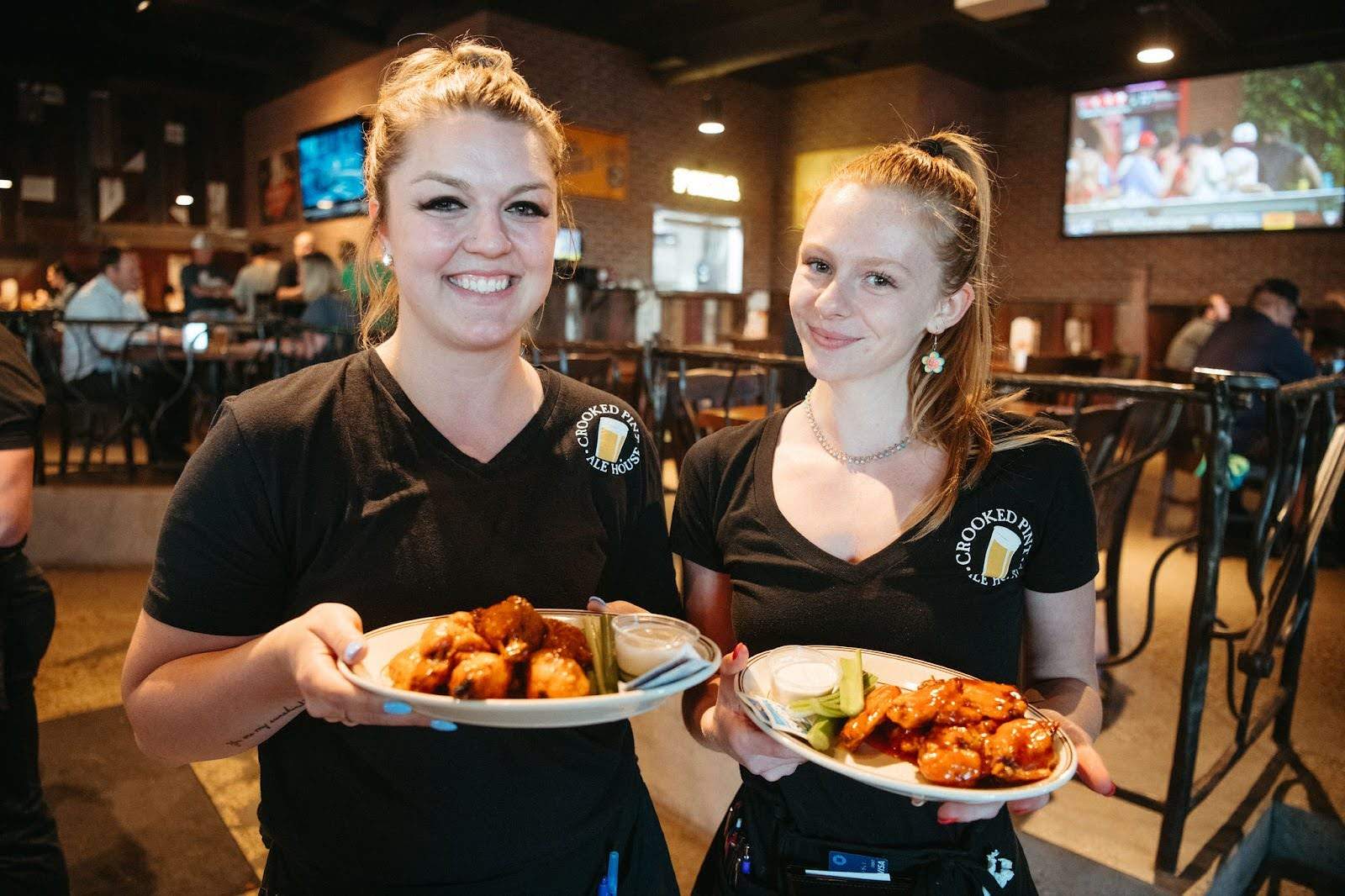 Two waitresses holding plates of food at Green mill restaurant & bar